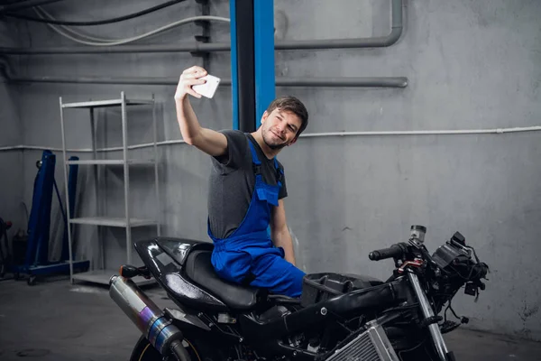 Bir tamirci motosikletle fotoğraf çeker.