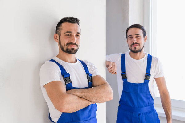Два строителя в синей рабочей одежде немного улыбаются