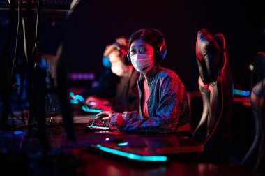 Coronavirus salgını sırasında, bir grup oyuncu üslerinde antrenman yapıyor, Asyalı bir kız ve diğerleri maske takıyor.