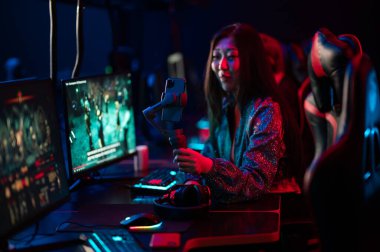 Esport arenasında neon ışığı var. Akıllı telefonuyla video blogu içeriği kaydeden, elinde telle Asyalı genç bir kızın portresi..