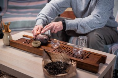 Arka planda bulanıklık olan yakın plan, eller sıcak kokulu çaydanlıktan özel merasim bardaklarına lezzetli bir çay döker..