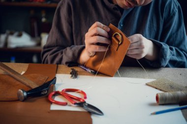 Ayakkabıcı atölyesindeki masaüstü. Deri ayakkabı yapma süreci. Yüzü olmayan eller yakın plan.
