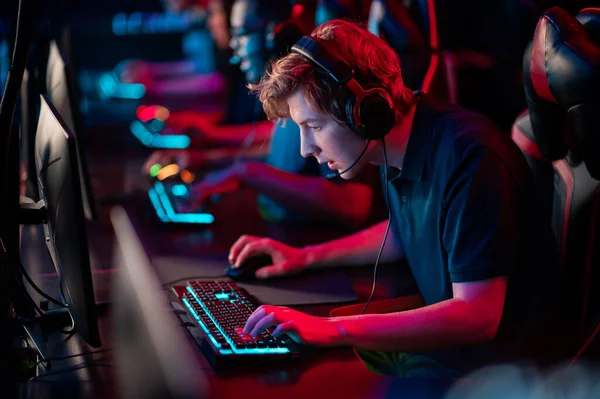 A multi-racial team of esports athletes conducts a training session before an online shooter tournament. Neon light. — Stock Photo, Image