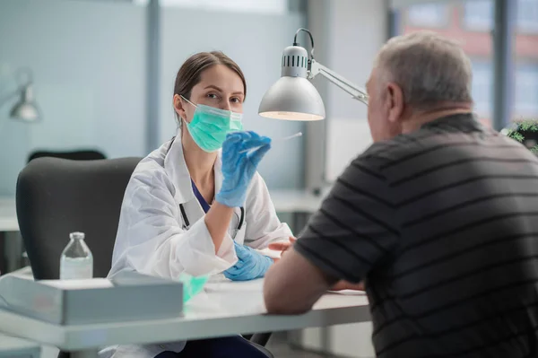 At the beginning of the medical appointment, a young nurse takes a swab from the mans nasopharynx, an analysis for covid-19 — Stock Photo, Image