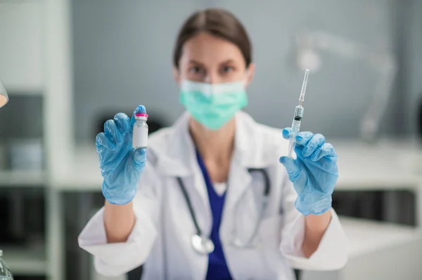 A young female lab technician wearing a medical mask shows off a coronavirus vaccine in her lab at the hospital