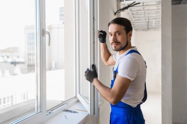 Ustabaşı açık pencerede durur ve gülümser.