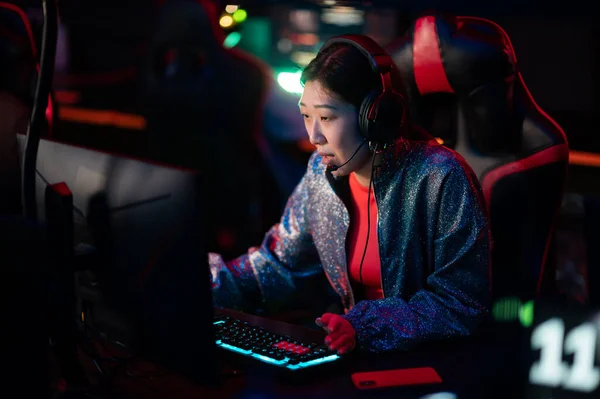 A young chinese esports player at an international esports tournament. A multi-racial cyber team is playing an online shooter game. Neon light. — Stock Photo, Image