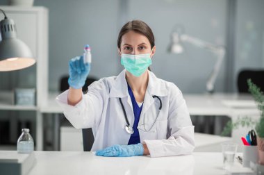 Hastanenin tedavi odasında, bir hemşire elinde bir aşı tutarak kovid 19 'a karşı halkı aşılamaya hazırlanıyor.