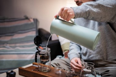 Bir adam misafirleri bekler ve çay seremonisi seti kullanarak otantik Çin çayı hazırlar. Çay ustasının talimatlarına göre taze çay yapraklarını sıcak suda demler..