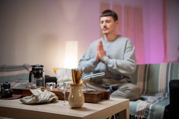 Meditating man on the sofa in the interior of the house. Complete immersion in the art of tea ceremony and traditional chinese rituals.