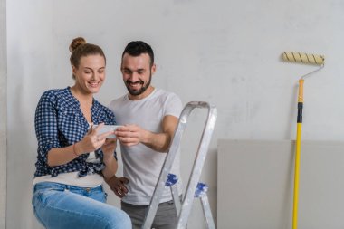 Kadın ve erkek merdivende oturup telefondaki fotoğraflara bakıyorlar.