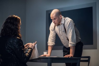 Suç işlediğinden şüphelenilen küstah bir adam soruşturma sırasında bir müfettişin önünde belgeleri yırtıp atıyor.