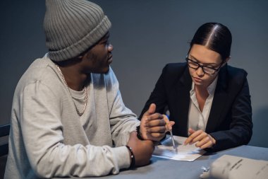 Sorgu odasında, uyuşturucu dağıtımı ve uyuşturucu bulundurma davasında bir şüpheli bir kamu avukatına danışır.