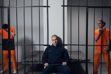 Üniformalı katı bir gardiyan yüksek güvenlikli bir hapishanede mahkumlarla birlikte hücreleri koruyor..