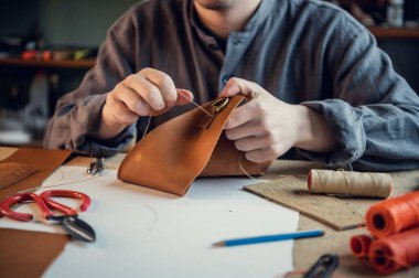 Ayakkabıcı atölyesindeki masaüstü. Deri ayakkabı yapma süreci. Yüzü olmayan eller yakın plan.