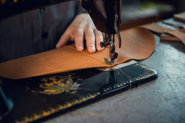 Photo en gros plan d'une couture de fil de haute qualité sur un morceau de cuir véritable marron. Mains d'un tailleur et d'une machine à coudre — Photo