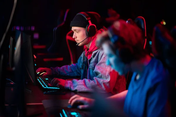 A multi-racial team of esports athletes conducts a training session before an online shooter tournament. Neon light. — Stock Photo, Image