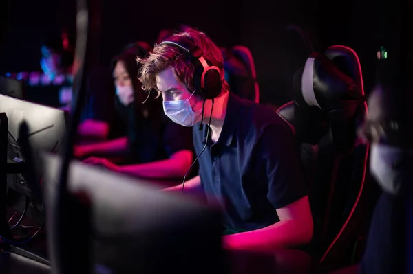 White-skinned and black-skinned guys are members of an esports online strategy crew. Play at the computer at an international tournament during the pandemic. — Stock Photo, Image