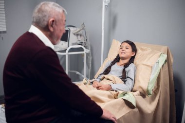 Hastane koğuşunda torununun yanında oturan son sınıf öğrencisi.