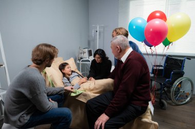 Akrabaları hastanede küçük bir kızı ziyaret ediyor, iyileşiyor.