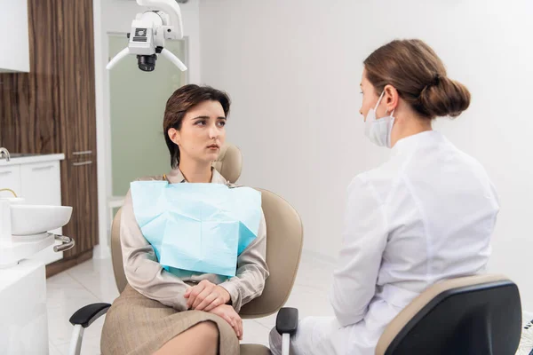 Een jonge vrouw klaagt bij haar tandarts in de tandheelkundige kliniek — Stockfoto