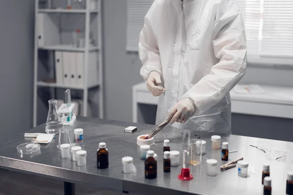 Um cientista a trabalhar num laboratório químico. Equipamentos de laboratório e artigos de vidro contendo líquidos químicos em primeiro plano — Fotografia de Stock