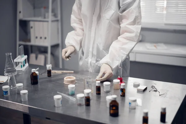 Químico a trabalhar num laboratório moderno. Close-up de uma pessoa que estuda uma reação química em uma mesa de laboratório com ferramentas de laboratório e substâncias coloridas — Fotografia de Stock
