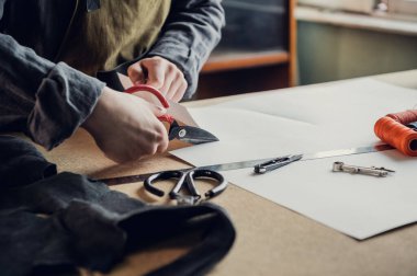 Ayakkabı üretim atölyesinde deneyimli bir ayakkabıcı, farklı aletlerle kağıttan bir ayakkabı modeli yapar.