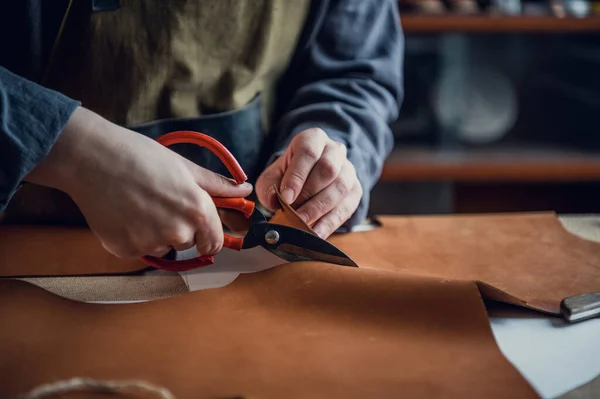 En la clase magistral para la producción de zapatos, un zapatero experimentado corta el cuero con tijeras — Foto de Stock
