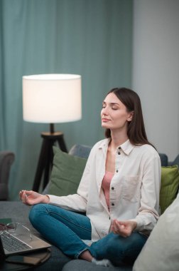 Evden uzakta çalışırken, kız tansiyonu düşürmek ve rahatlamak için Lotus Asana 'daki kanepede oturdu.