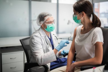 Maskeli deneyimli bir doktor aşıyı ofisinde özel bir klinikte yapar.