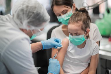 Şefkatli bir anne aşıyı yaptırmak için kızını aşı odasına getirdi.