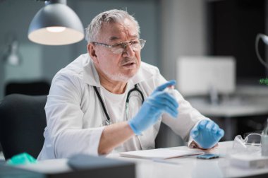 Resepsiyondaki yaşlı bir doktor, hastaya özel bir klinikte teşhis ve tedavi hakkında danışmanlık yapar.