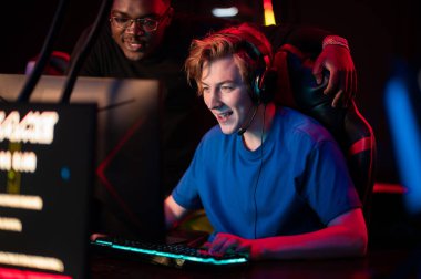 Tecrübeli bir esportçu koyu tenli arkadaşına bilgisayar kulübünde nasıl oyun oynanacağını gösterir.