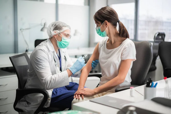 Un joven estudiante de medicina inyecta una vacuna contra el coronavirus en el hombro de una niña — Foto de Stock