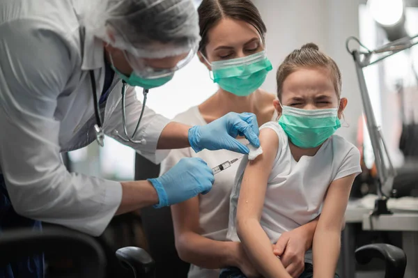 Um médico dá uma injeção no ombro a uma garota assustada para prevenir doenças infecciosas — Fotografia de Stock