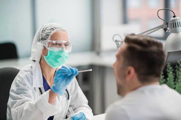 Özel bir klinikteki bir laboratuvar asistanı, hastaların nazofarinksinden örnek alır. Coronavirüs covid 19 için bir PCR testi.