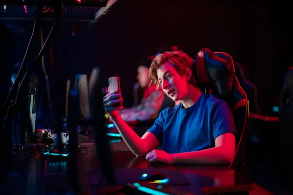 A young esports player records a video on his phone for his vlog from the training base of his team of gamers — Stock Photo, Image