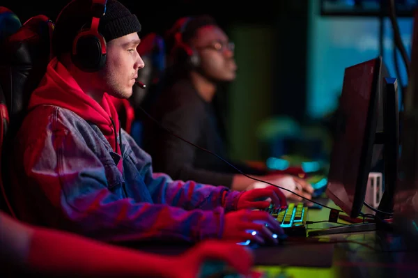 A multi-racial team of esports athletes conducts a training session before an online shooter tournament. Neon light. — Stock Photo, Image