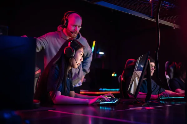 Esports team training camp in computer club with coach, caucasian guy and asian girl — Stock Photo, Image