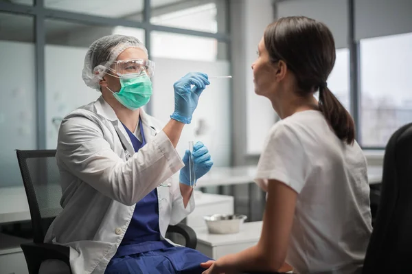 À l'aide d'un coton-tige, l'assistant de laboratoire prélève le contenu du rhinopharynx du client pour détecter le coronavirus. Image En Vente