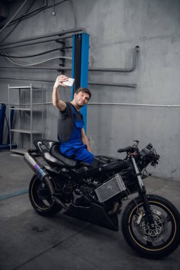 Bir işçi motosikletle fotoğraf çeker.