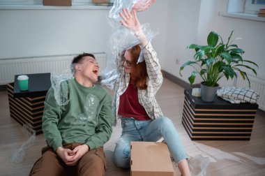 Bir erkek ve bir kız yeni evlerindeki kutuları açarken eğleniyorlar, mutlular.