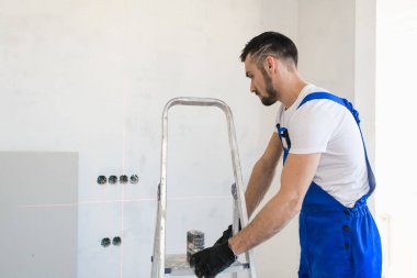 Tulumlu müteahhit merdiveni duvara taşıyor.