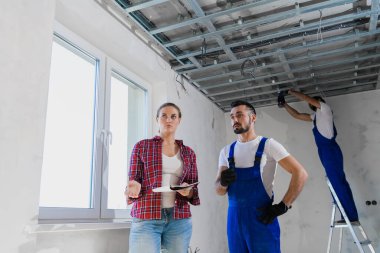 Müşteri dairedeki işçilerin işlerini kontrol eder ve bir not yazar.