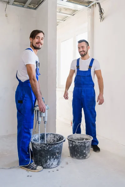 Two workers knead cement with a construction mixer — Stock Photo, Image