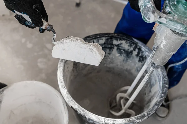 Arbeiter steckte trockenen Zement mit einem Spachtel in einen Eimer — Stockfoto
