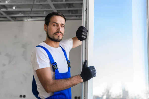 Trabalhador em luvas instala a janela no apartamento — Fotografia de Stock