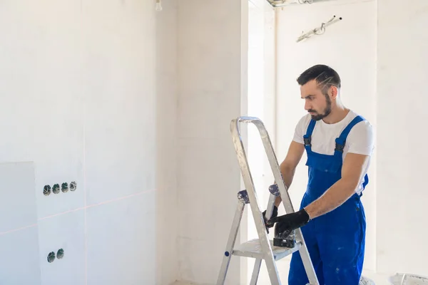 El reparador utiliza una escalera y un nivel de láser — Foto de Stock