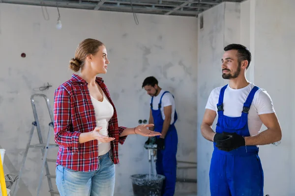 Üniformalı adam, kadına dairenin nasıl yenilendiğini gösteriyor.